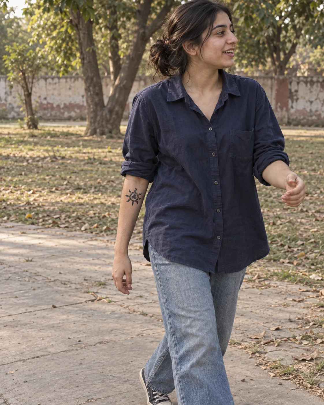 A young Pakistani woman wearing a turtle temporary tattoo on a garden walk