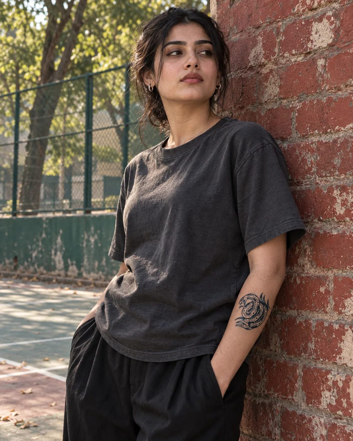A young Pakistani woman wearing a snake temporary tattoo beside a Lahore sports court